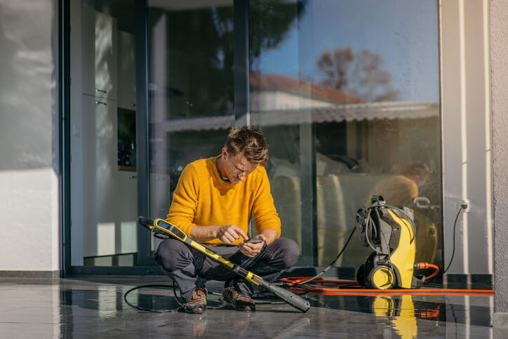 Pressure washing professional checking his pressure washing app to input details about a job.