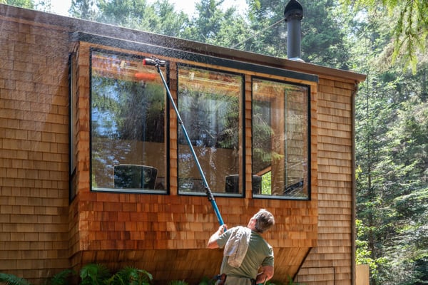 Professional window cleaner working on the exterior windows of a house