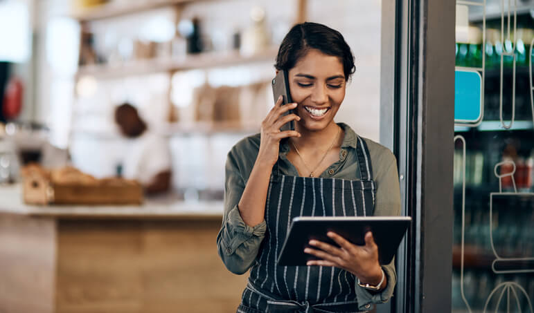 A franchise business owner smiling while on the phone and holding a tablet.