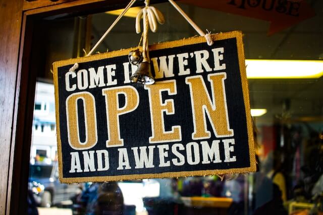 A local business door sign that says come in we're open and awesome.