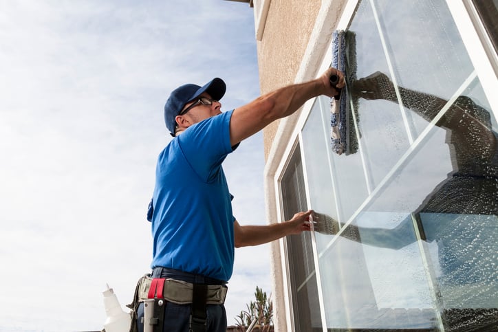 Professional window cleaner cleaning a residential exterior window.