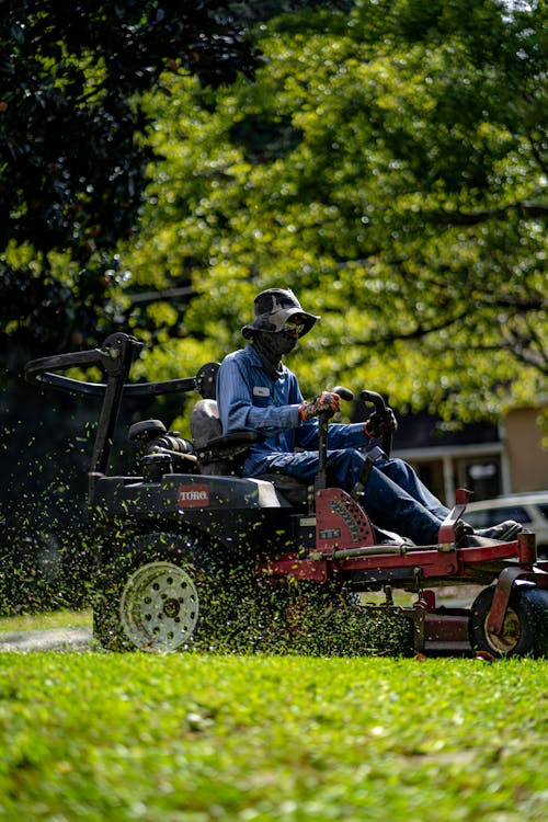 landscaper mowing lawn with a big mower